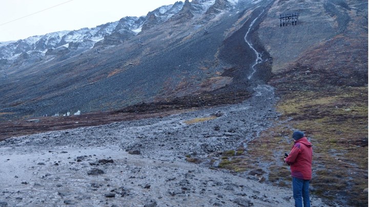 Skred i aktivlaget i fjellsiden i Longyeardalen i oktober 2016. Skredet kom ned bare 20 meter fra kirkegården, som også ses på bildet. Personen står på veibanen, som ble helt blokkert av skredmassene.