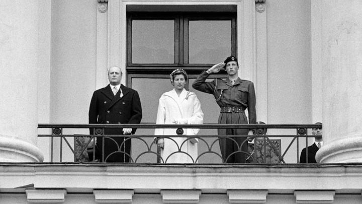 Slik så det ut i 1956 da daværende prins Harald gjorde honnør i uniform fra slottsbalkongen. Han står her sammen med daværende kronprins Olav og prinsesse Astrid.